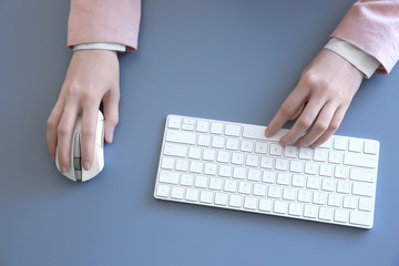 Wall Mural - Female hands with computer mouse and keyboard on grey table