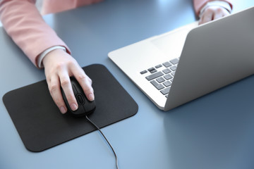 Wall Mural - Woman using computer mouse with laptop on table