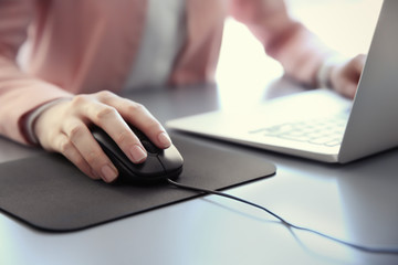 woman using computer mouse with laptop on table