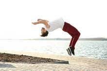 Young Sporty Man Doing Acrobatic Exercises Near River
