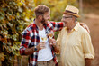 © luckybusiness - Father and son tasting wine in vineyard.