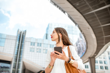 Young businesswoman standing with phone near the Parliament building of European Union in Brussel city