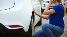 Looking At A Damaged Vehicle. Woman Blonde Inspects Car Damage After An Accident