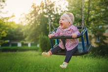 Shifting The Little Baby Girl On Swings On A Summer Evening.