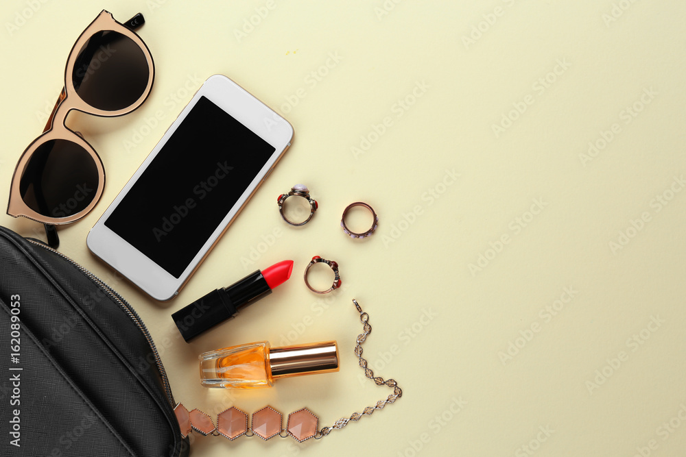 Perfume bottle with cosmetic bag and phone on color background