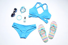 Blue Bikini And Beach Accessories On White Background