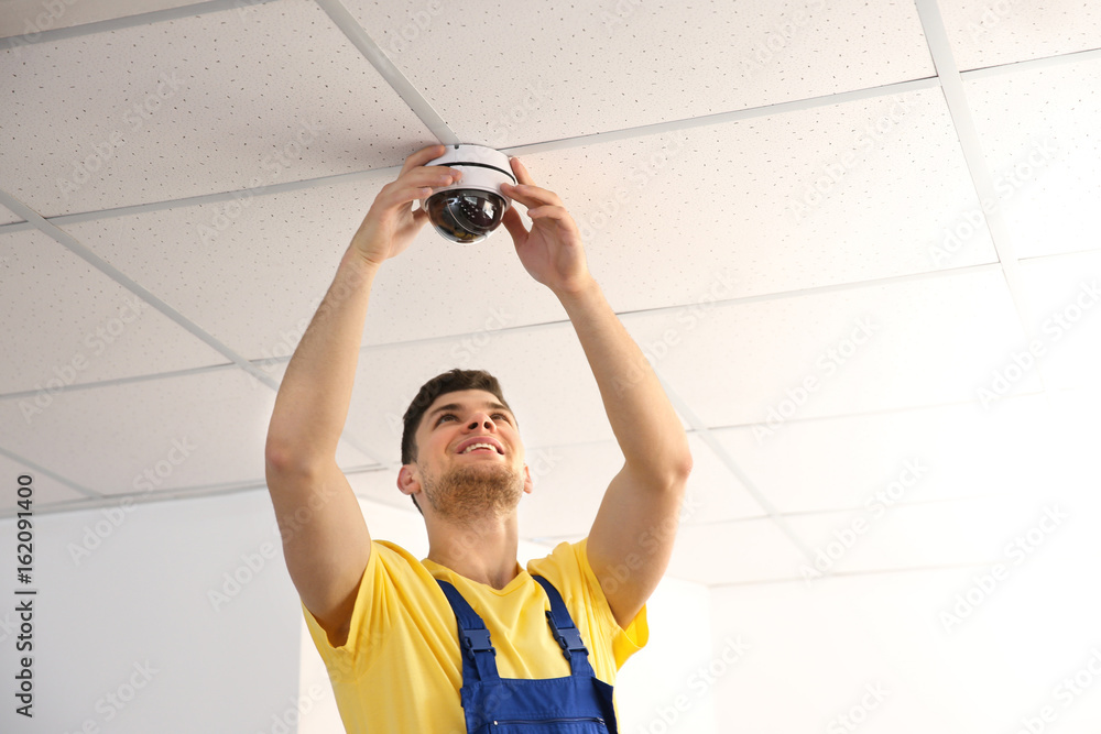 Electrician fixing video surveillance camera indoors