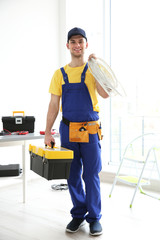 Wall Mural - Young electrician with tools and wires at workplace