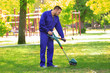 © Africa Studio - Young worker mowing lawn with grass trimmer outdoors on sunny day