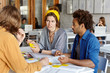 © WHstudio Leushin N - Pretty college student female with yellow scarf on head listening to her groupmates disagreeing with their suggestions frowning her face. Group of students of different races talking about studying