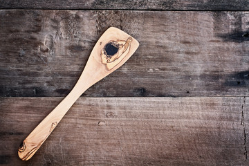 High angle view of a old olive wood spatula over a rustic wooden background. Available copy space for text.