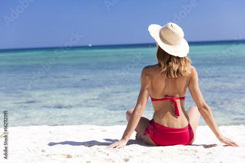 Zdjęcie XXL kobieta w stroju kąpielowym siedzi z tyłu z widokiem na morze