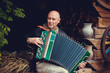 © T.Den_Team - Mature man plays on a musical instrument accordion , is dressed in an embroidered shirt. Unification of the  Slavs on abroad