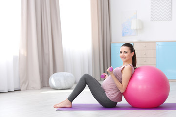 Beautiful pregnant woman doing exercise at home