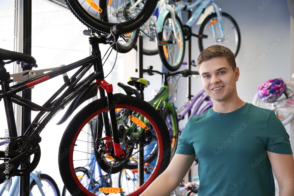 Smiling young man standing in bicycle shop