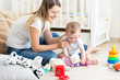 © Кирилл Рыжов - Young mother playing on floor with her baby boy at living room