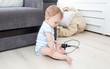 © Kyrylo Ryzhov - Concept of parent irresponsibility. Baby boy sitting alone and playing with electrical cables