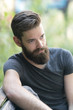 © cineberg - Thoughtful bearded guy sitting on a bench in park