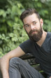 © cineberg - Thoughtful bearded guy sitting on a bench in park
