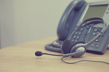 Wall Mural - close up soft focus on telephone devices and call center headset at office desk of customer service support concept