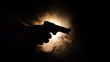 Male hand holding gun on black background with smoke ( yellow orange red white ) colored back lights, Mafia killer concept