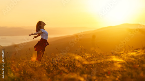 Plakat Szczęśliwa kobieta na zmierzchu w naturze w lecie z otwartymi rękami
