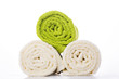 Two white towels and one green rolled into a roll on a white background