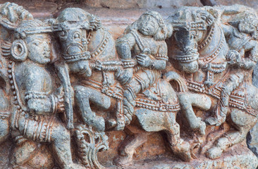 Wall Mural - Warriors and horseriders on stone sculptures of decoration inside the Hindu temple. Walls with artworks and designed patterns of 12th centur Hoysaleshwara temple in Halebidu, India.