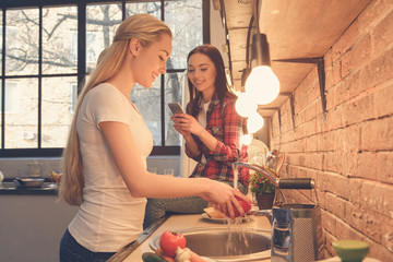 Young women friends cooking meal together at home