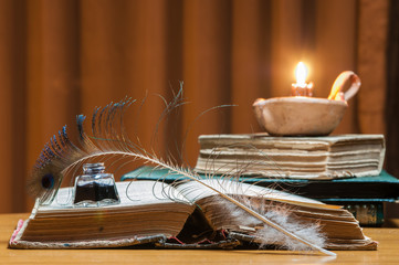 Quill pen, old papers and books by candle light