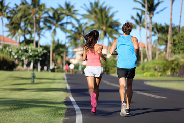 Runners athletes running training legs on road in residential neighborhood. Two people exercising together in summer city outdoors. Couple working out cardio.