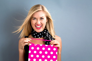 Wall Mural - Happy young woman holding a shopping bag on a gray background