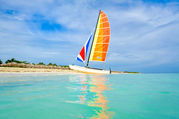 Wall Mural - The tropical beach of Varadero in Cuba with a colorful sailboat