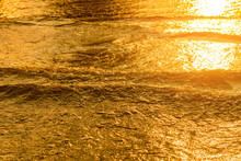 Golden Light Reflecting Off A Water Wave At The Sea And Sand On Sunset. Pure Gold Tone