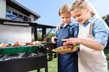 Wall Mural - adorable children testing fresh meat just cooked on barbecue grill outdoors