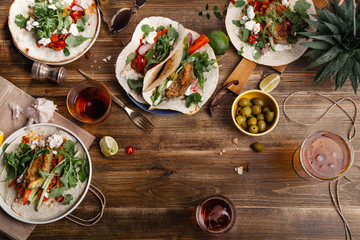 Tacos with fried avocados , tomatoes and greens on distressed wooden background. Served with beer, lime and olives. Mexican cuisine interpretation. Horizontal composition with copy space.