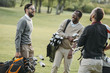 Multiethnic golf players with golf clubs having fun on golf course