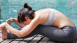 Professional asian woman practice yoga sequence Seated Forward Bend Pose (Paschimottanasana) close up portrait beside swimming pool blue water