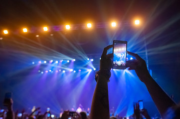 Wall Mural - People in the crowd at a concert make video recordings and pics on a smartphone of published in social networks