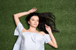 © LIGHTFIELD STUDIOS - above view of young attractive woman looking at camera while lying on the grass