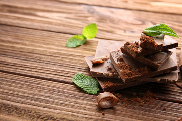 Wall Mural - Dark chocolate pieces with mint leaves on wooden table