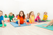 © Sergey Novikov - Kids stretching backs on yoga mats in sports club