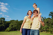 © Studio Romantic - Happy family smiling in the park. Mother, father and daughter in nature on background of blue sky and trees.