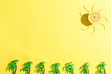 Wall Mural - Palm trees and lemon sun flat lay on yellow background