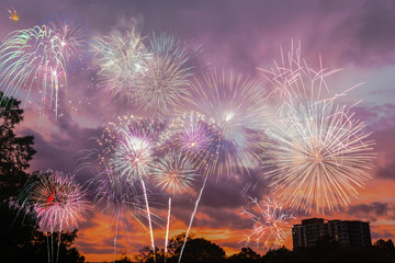 Beautiful colorful holiday fireworks in the sunset/evening sky with majestic clouds, long exposure. Concept of American Independence celebration. Happy Independence Day or Fourth of July banner.