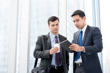 Wall Mural - Businessmen looking at tablet computer discussing work in office building hallway