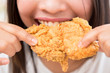 Young woman eating deep fried chicken - close up shot