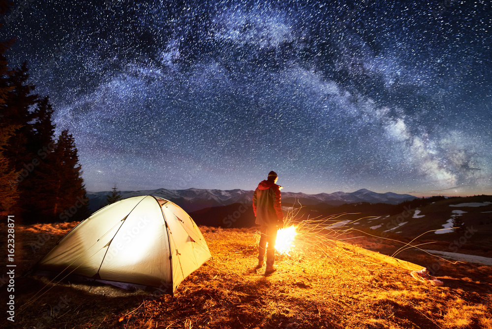 Male tourist have a rest in his camp near the forest at night. Man ...