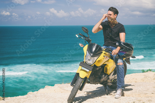 Plakat Nowożytny przystojny mężczyzna pozuje z jego motocyklem.