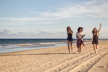 Canvas Print - Group of three beautiful young women walking on the beach